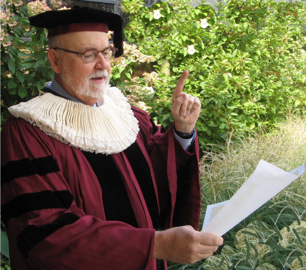 Dean Antczak in academic regalia and an Elizabethan ruff reading the proclamation